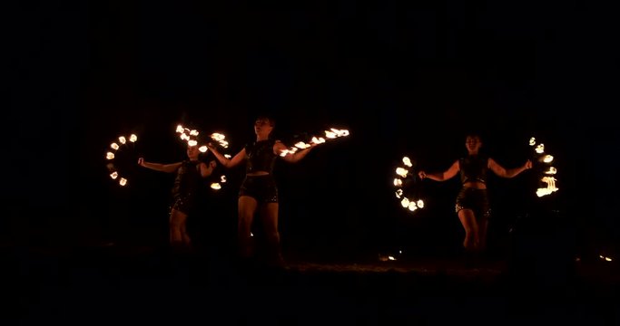Group of fire jugglers. People spit fire in a dark night outdoors performance
