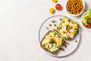 Breakfast toasts, soft scrambled eggs avocado goat cheese spicy chickpeas. Top view, space for text.
