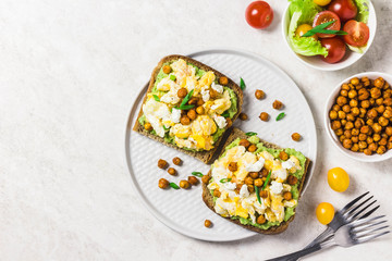 Breakfast toasts, soft scrambled eggs avocado goat cheese spicy chickpeas. Top view, space for text.