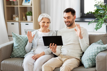 Obraz premium family, generation and people concept - happy smiling senior mother and adult son having video chat on tablet computer at home