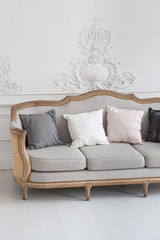 Luxurious bright Rococo interior with a large sofa and stucco on the walls. Close up. Selective focus.