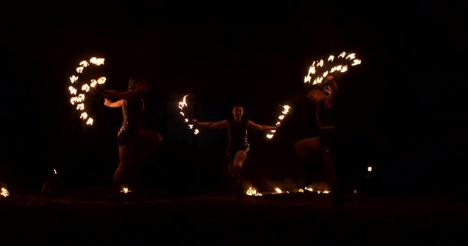 Group of fire jugglers. People spit fire in a dark night outdoors performance