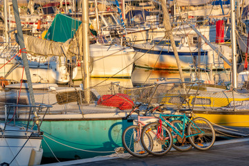 Fototapeta na wymiar Colorful bicycles and sailing boats at sunset in the harbor of La Rochelle, France