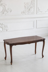 Vintage coffee table in the Rococo style with wood carvings in a luxurious interior with stucco. Selective focus.