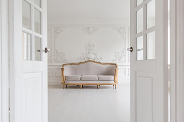 Luxurious bright Rococo interior with a large sofa and stucco on the walls. Selective focus.