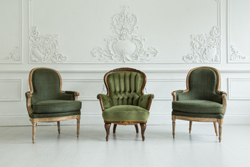 Living room in the Rococo style. Vintage chairs against the wall with plaster stucco patterns. Selective focus.