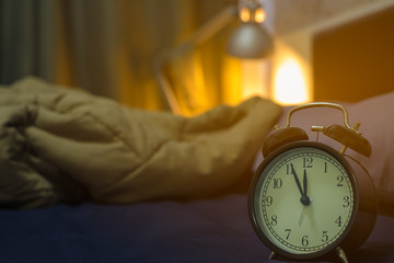 Five minutes before midnight. Close-up of Retro alarm black clock vintage style on the bed room in...