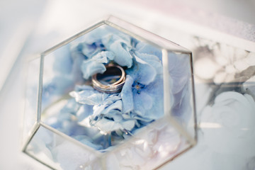 wedding rings are in a wooden box with flower petals
