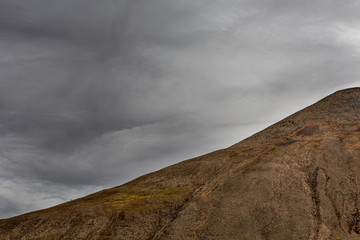 one single hiker climbing to the top of Gruvefjellet mountain, Svalbard landscape, view from across...