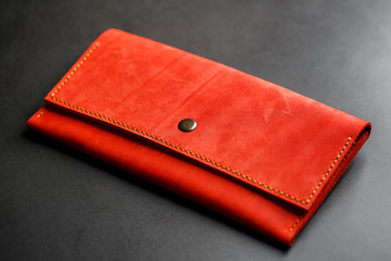 Red leather wallet on a dark background top view. Close-up, purse details, rivet and firmware