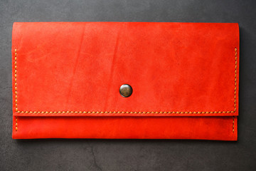 Red leather wallet on a dark background top view. Close-up, purse details, rivet and firmware