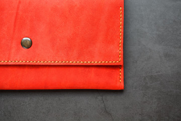 Red leather wallet on a dark background top view. Close-up, purse details, rivet and firmware