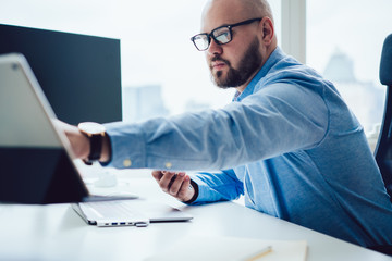 Modern man using tablet at computer desk