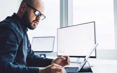 Contemporary bearded worker with gadgets at table