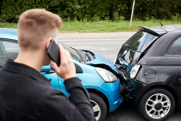 Fototapeta na wymiar Young Male Motorist Involved In Car Accident Calling Insurance Company Or Recovery Service