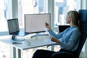Hardworking woman with papers at computer desk