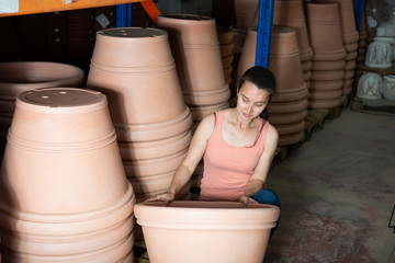 Woman chooses pots clay pots in store warehouse