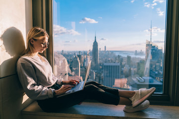 Concentrated female freelancer keyboarding information on laptop computer working remote in...