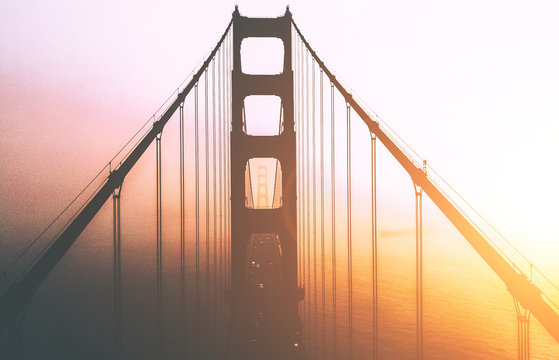 Beautiful Aerial view silhouette of famous San Francisco landmark with name Golden Gate bridge. Scenery bridge tower construction in misty foggy sunset light. Famous California sight in gold sundown