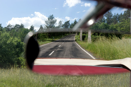 Asphalt road in the rearview mirror. Rear view mirror in the Cabriolet