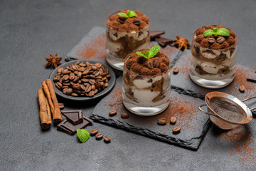 Classic tiramisu dessert in a glass on stone serving board on dark concrete background