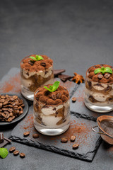 Classic tiramisu dessert in a glass on stone serving board on dark concrete background