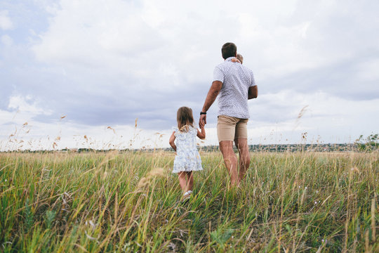 adorable toddler hugging his father and holding his neck and walking his daughter