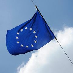 A flag of european union is flying on a background of blue sky with white clouds
