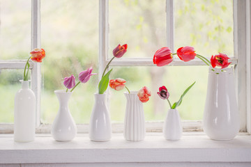 spring flowers in white vase on old windowsill