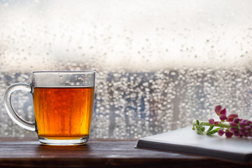cup of tea on  background of  window with raindrops at sunset