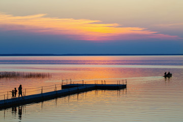 Fototapeta premium summer sunset on lake wit family and boat