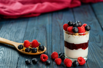 The healthy breakfast of yogurt with muesli, granola rasberry jam and fresh fruits rasberry and blueberry