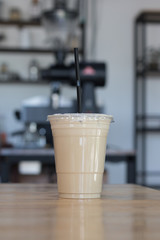 Iced milk coffee in plastic cup with straw and cover.Indoor cafe