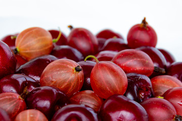 Gooseberries and wild cherry berries on a light background