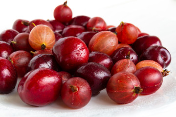 Gooseberries and wild cherry berries on a light background
