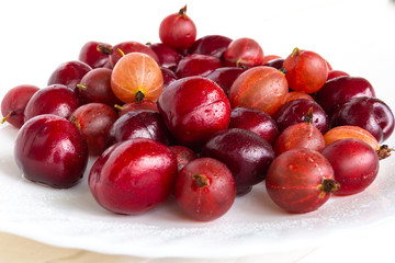 Fototapeta na wymiar Gooseberries and wild cherry berries (gean) on a light background