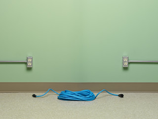 Blue coiled extension cord with two outlets to choose from on green wall