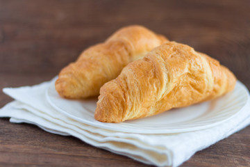 fresh delicious croissants on a plate on a wooden background