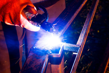 Welder worker performs jump welding. Man welder in protective gloves performs arc-welding process...