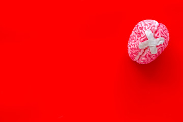 Disease of the brain concept with brain with cross-shaped patch on red background top view