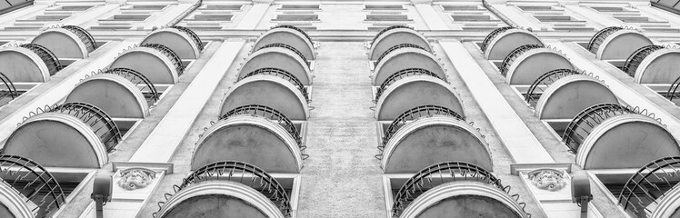 Balconies of a high-rise building. Bottom view. Architectural elements. Modern building in classic style. Multi-storey building. Black and white retro toning.