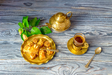 Eastern sweets "baklavadakia" and a cup of coffee on a wooden background