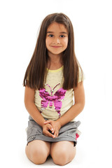 Portrait of a smiling little girl sitting on knees. Isolated on white background