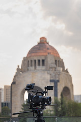 C&aacute;mara de video con monitor en una terraza en primer plano con el Monumento a la Revoluci&oacute;n al fondo.