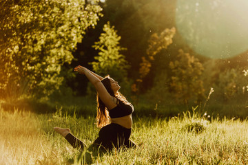Beautiful plus size girl doing yoga in nature on a sunny summer day. Body positive, sports for...