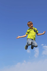 Junge springt in die Luft, im Hintergrund blauer Himmel