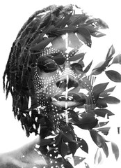 Double exposure of a dark skinned man with dreadlocks and face paint combined with a photograph of...