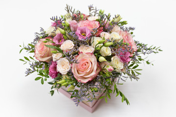 delicate floral arrangement of roses and live decorations in a square cardboard box (primary color - pink) on a light background