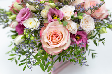 delicate floral arrangement of roses and live decorations in a square cardboard box (primary color - pink) on a light background