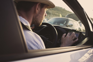 Man in car uses smartphone for navigation. Driving on vacation